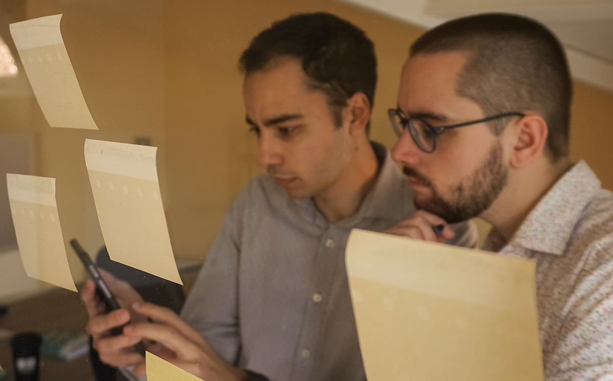 Two men looking at a Scrum Board in a daily standup meeting